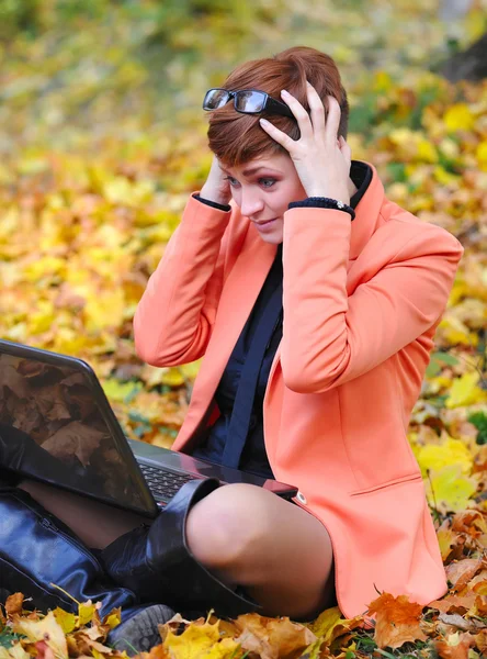 Mujer linda con portátil en el parque de otoño — Foto de Stock