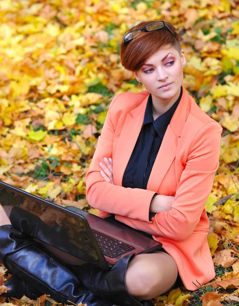 Nette Frau mit Laptop im Herbstpark — Stockfoto