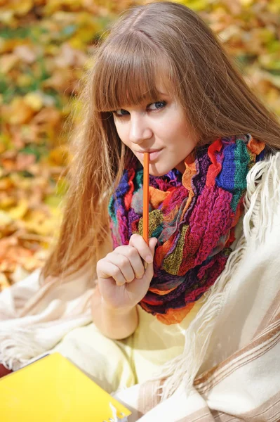 Bella ragazza con taccuino su uno sfondo foglie di autunno — Foto Stock