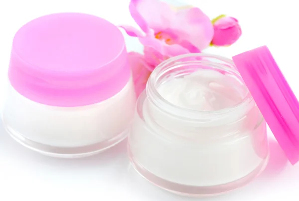 Cremes cosméticos e flores rosa isoladas sobre fundo branco — Fotografia de Stock