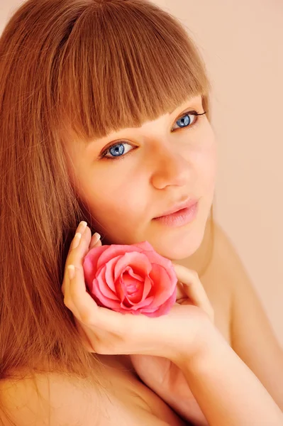 Schönes Mädchen mit Rosenblüte, das ihr Gesicht berührt. Hautpflegekonzept — Stockfoto