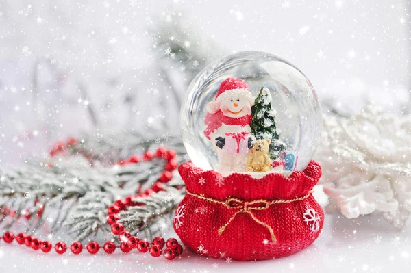 Un globe de neige avec bonhomme de neige sur fond branches d'épinette avec sno — Photo