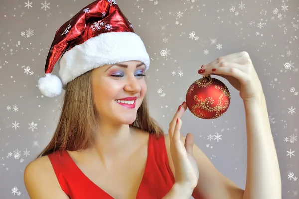 Attractive young woman holding red Christmas ball — Stock Photo, Image