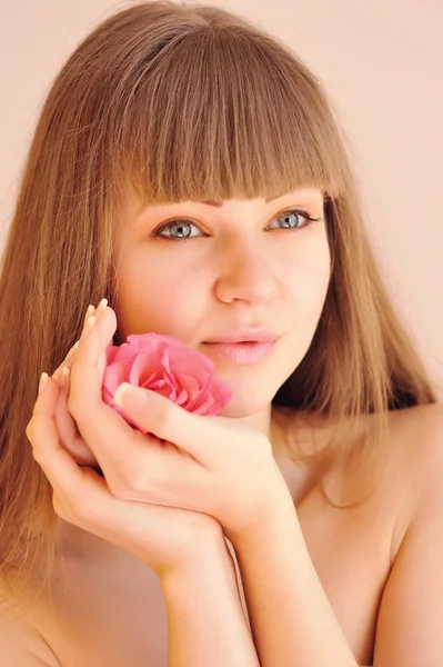 Hermosa chica con flor rosa tocando su cara. Concepto de cuidado de la piel —  Fotos de Stock