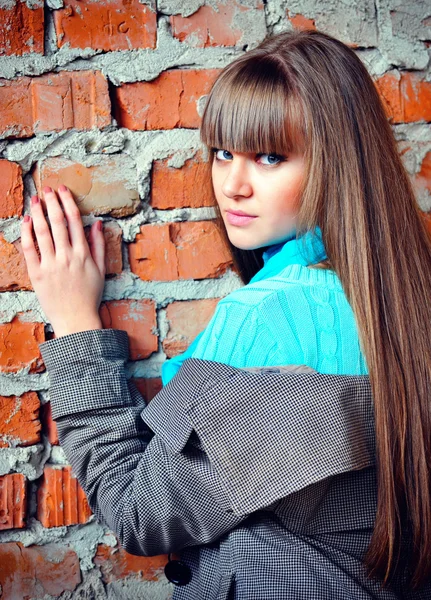 Mooie jonge vrouw in de buurt van een bakstenen muur — Stockfoto