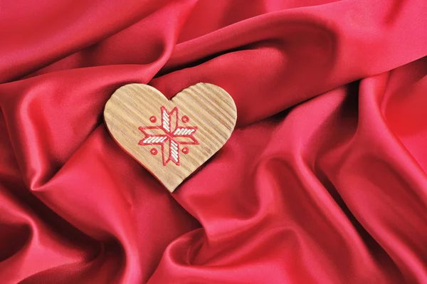Trä hjärta på röd satin bakgrund — Stockfoto