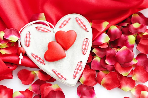 Hearts on a background of red petals and satin — Stock Photo, Image