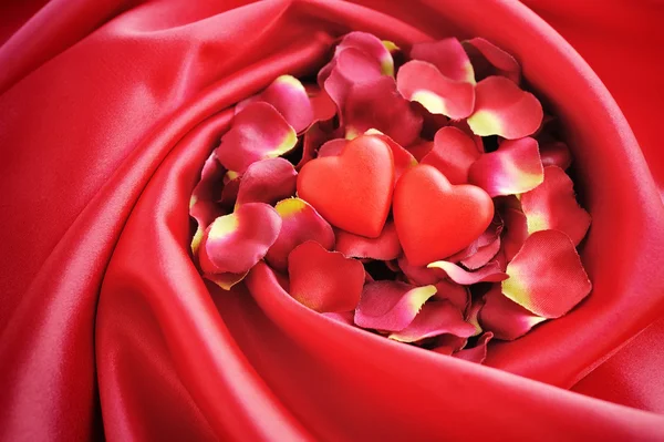 赤い花びらとサテンの背景に二つの心 — ストック写真
