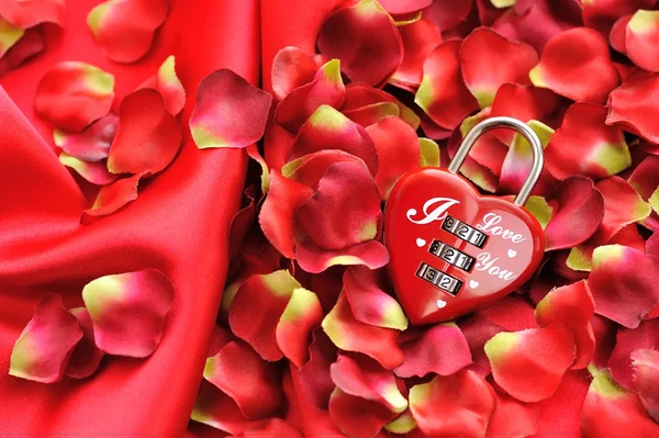 Cadenas en forme de coeur sur fond de pétales rouges et de satin — Photo