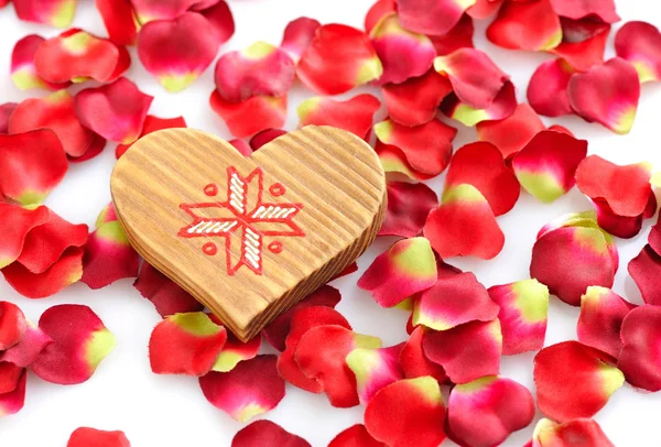 Corazón de madera sobre un fondo de pétalos rojos — Foto de Stock