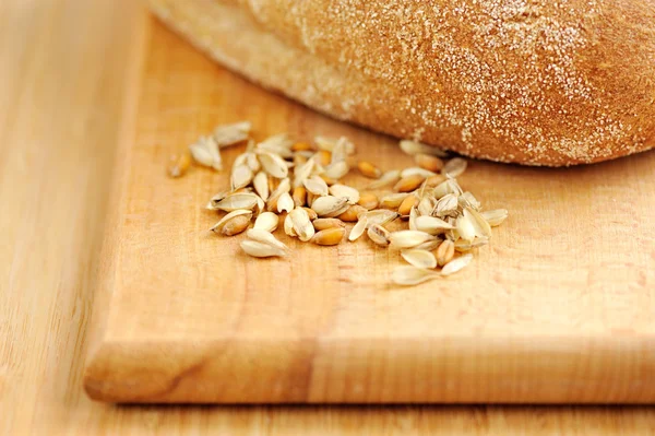 Wheat on wooden board with bread — Stock Photo, Image