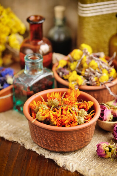 Исцеление трав и настойки в бутылках на мешковине, сушеных цветах, травяной медицине
