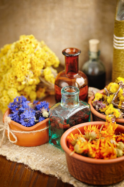 Исцеление трав и настойки в бутылках на мешковине, сушеных цветах, травяной медицине
