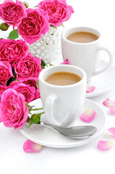 Šálky kávy a růžových růží na bílém pozadí — Stock fotografie