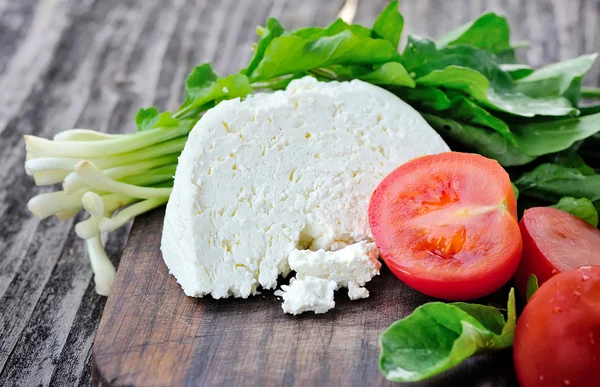 Сыр с помидорами и луком на деревянной доске — стоковое фото