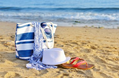 şapka, çanta, güneş gözlüğü ve kumlu bir plaj üzerinde flip flop. VA yaz