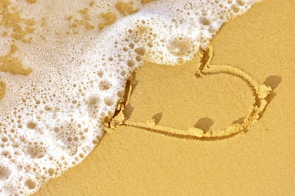 Welle spült Herz in den Sand — Stockfoto