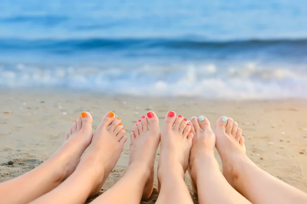 Жіночі ноги з кольоровим педикюром на фоні моря — стокове фото