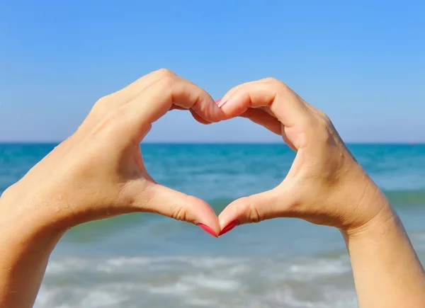 Female hands in the shape of heart on the background sea — Stock Photo, Image