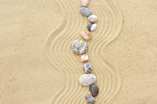 Gestreepte stenen op het zand, kan worden gebruikt als achtergrond — Stockfoto