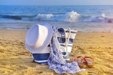 şapka, çanta, güneş gözlüğü ve kumlu bir plaj üzerinde flip flop. VA yaz