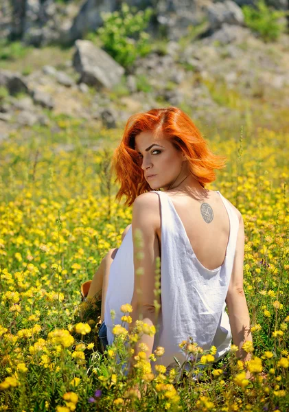 Belle jeune fille parmi les fleurs sauvages jaunes — Photo