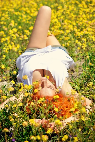 Szép boldog lány fekszik között sárga vadvirágok — Stock Fotó