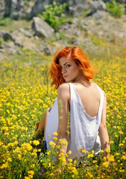 Hermosa joven entre flores silvestres amarillas — Foto de Stock