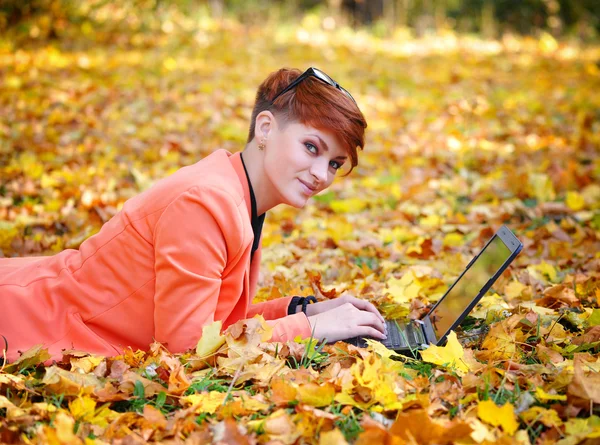 Nette Frau mit Laptop im Herbstpark — Stockfoto