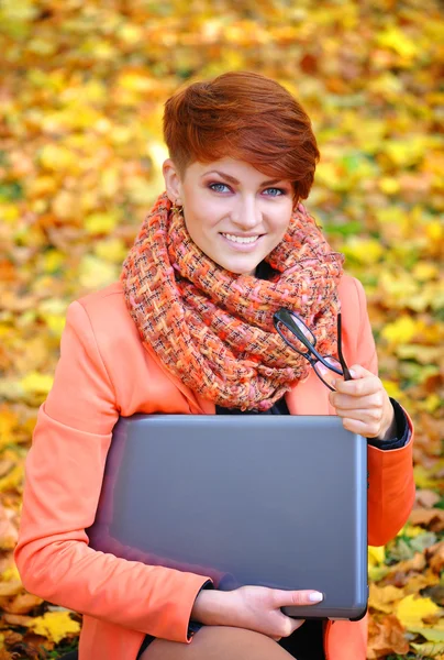 Leuke vrouw met laptop in de herfst park — Stockfoto