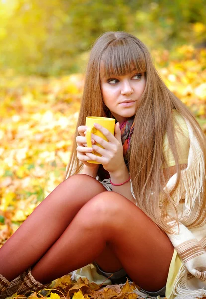 Young beautiful woman that holds the cup of tea in hands on a ba — Stock Photo, Image