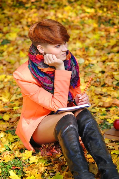 Φοιτητής κοκκινομάλλης κορίτσι με σημειωματάριο σε ένα φόντο φθινόπωρο lea — Φωτογραφία Αρχείου