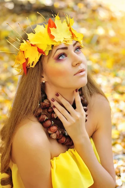 Retrato de una hermosa niña en una corona de hojas de otoño — Foto de Stock