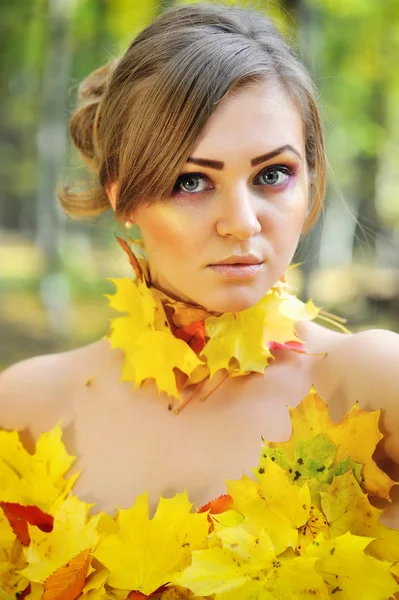 Portret van een mooie jonge vrouw in de herfst bladeren — Stockfoto