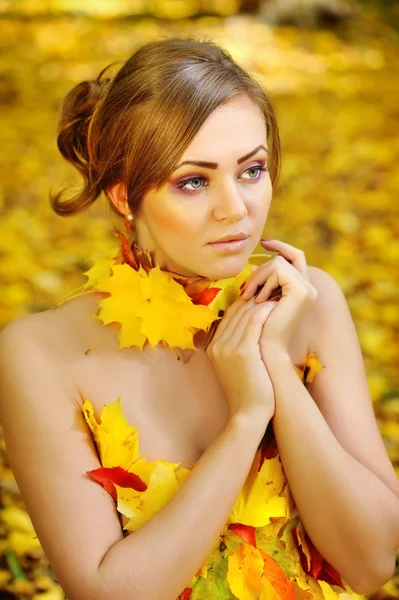 Retrato de una hermosa joven en hojas de otoño — Foto de Stock