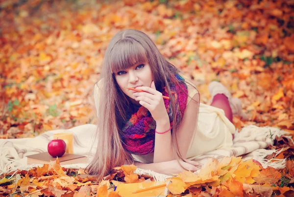 Schöne Mädchen mit Notizbuch auf einem Hintergrund Herbstblätter — Stockfoto