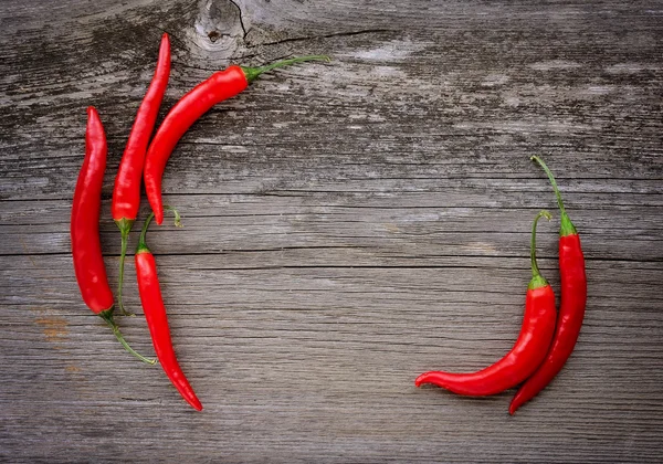 Rode hot chili peppers op oude houten tafel met plaats voor tekst — Stockfoto