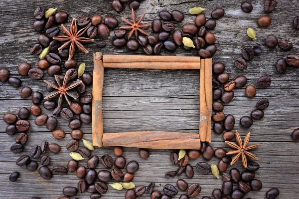 Anis estrela e canela varas no quadro feito de grãos de café torrados em fundo de madeira para texto ou imagem — Fotografia de Stock