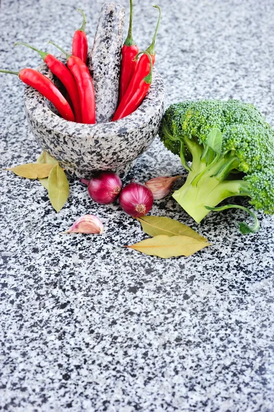 Mortaio di pietra e pestello con verdure su un tavolo di granito — Foto Stock