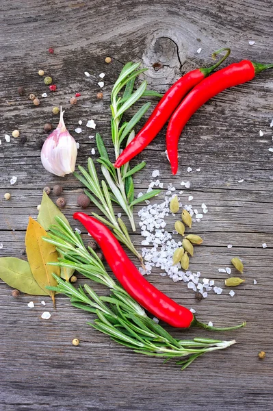 Zelenina a koření na dřevěné pozadí. Chilli, rozmarýn, sůl, pepř, Vavřín, kardamom, česnek — Stock fotografie