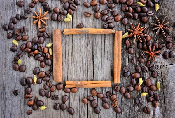 Stella di anice e cannella bastoncini nella cornice a base di chicchi di caffè tostati su sfondo di legno per testo o immagine — Foto Stock