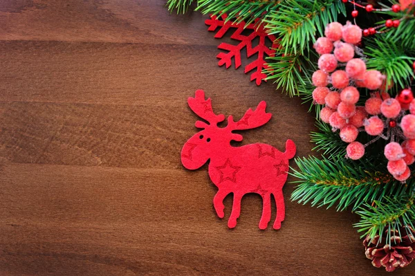 Vánoční figurka losů a smrkové větvičky na dřevěné pozadí — Stock fotografie