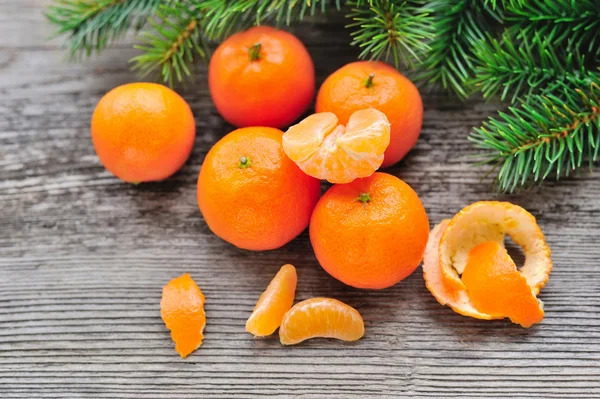 Tangerines and fir branches on old wooden background — Stock Photo, Image