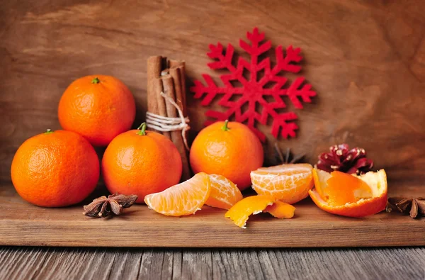 Tangerini e decorazioni natalizie, anice stellato, bastoncini di cannella su fondo di legno — Foto Stock
