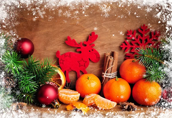 Tangerini e rami di abete con decorazioni natalizie su sfondo di legno — Foto Stock