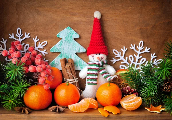 Bonhomme de neige aux mandarines et branches de sapin et décorations de Noël sur fond de bois — Photo