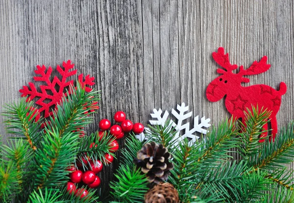 Christmas decorations and spruce twigs with cones on the old wooden background — Stockfoto