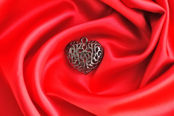 Heart pendant on satin fabric background — Stock Photo, Image