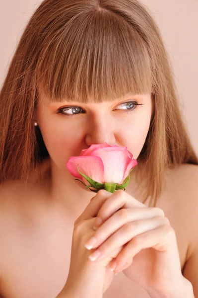 Schönes Mädchen mit Rosenblüte, das ihr Gesicht berührt. Hautpflegekonzept — Stockfoto