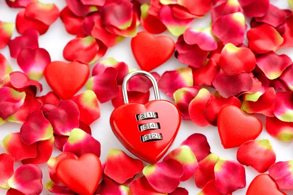 Padlock heart-shape on a background of red petals — Stock Photo, Image